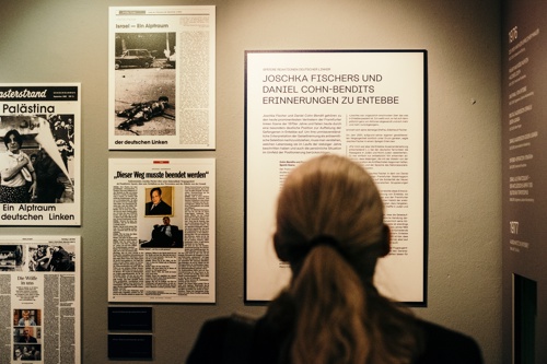A person looks at an exhibition board and newspaper clippings